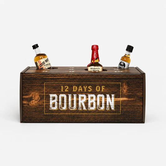 A dark brown advent calendar gift box engraved with '12 DAYS OF BOURBON' in white and gold lettering, with three miniature liquor bottles placed on top against a light gray background.